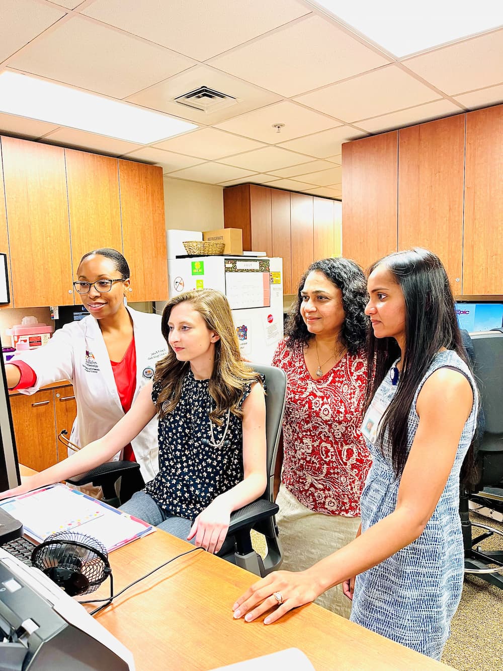 Allergy faculty and students stading at a workstation looking at a computer screen.